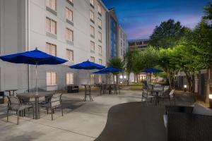 a patio with tables and chairs with blue umbrellas at Holiday Inn Express & Suites Memphis East by IHG in Memphis