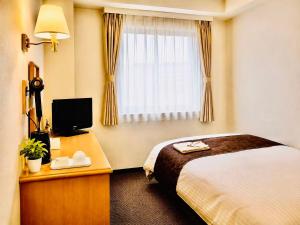 a hotel room with a bed and a window at Saga Idaimae Green Hotel in Saga