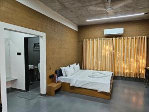 a bedroom with a white bed and a window at Shunyata Eco Resort Junagadh in Vadal +12 photos