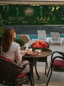 a woman sitting at a table with a plate of food at Kohinur Plaza in Samarkand