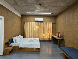 a bedroom with a bed and a desk in it at Shunyata Eco Resort Junagadh in Vadal