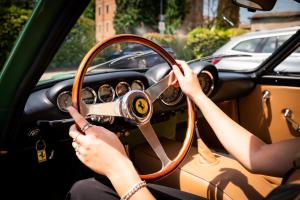 a woman driving a car with her hands on the steering wheel at Maranello Palace in Maranello