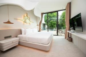 a bedroom with a bed and a tv and a window at The Rachata at Ayothaya in Ban Khlong Takhian