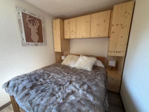 a bedroom with a bed and wooden cabinets at Le cocon dans les nuages in Lélex
