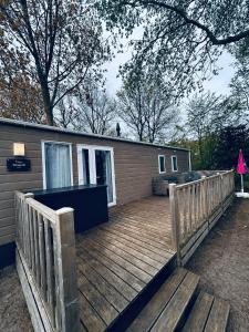 a home with a wooden deck with a house at Chalet am Wattenmeer Holland in Lauwersoog