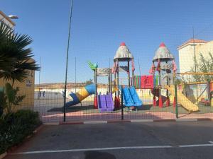 a playground behind a fence with a play structure at Marinamer 1 in Saïdia