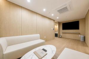 a living room with a white couch and a flat screen tv at 제니스 호텔 in Jecheon