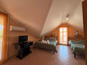 a attic room with two beds and a television at Themis Rooms in Nea Vrasna
