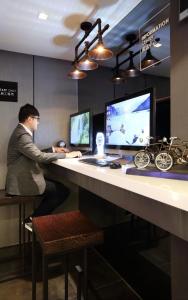 een man aan een bureau met twee computers bij Long View Hotel in Tamsui