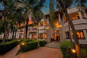 a building with palm trees in front of it at Rawai Grand House -SHA Plus in Rawai Beach