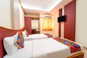 a hotel room with two beds and a television at FabHotel Grand Gunas in Coimbatore