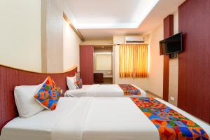 a hotel room with two beds and a flat screen tv at FabHotel Grand Gunas in Coimbatore