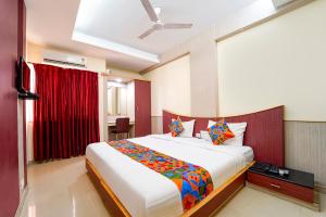 a bedroom with a large white bed with colorful pillows at FabHotel Grand Gunas in Coimbatore