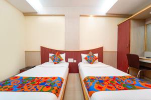 a room with two beds with colorful pillows at FabHotel Grand Gunas in Coimbatore +27 photos