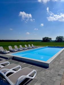 a swimming pool with lounge chairs and a swimming poolvisor at Blisko Natury Jacuzzi & Sauna in Pisz