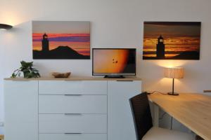 a desk with a television on top of a white cabinet at Weber19 - Haus Hammerich in Wenningstedt