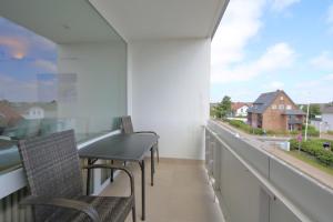 a balcony with chairs and a table and a window at Weber19 - Haus Hammerich in Wenningstedt