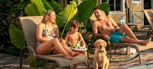 Eine Familie sitzt auf Gartenstühlen neben einem Hund in der Unterkunft Hotel Pousada Iracemar, 60m da Praia da Enseada, Piscina Aquecida ao Ar Livre para Relaxar em Qualquer Estação, Café da Manhã, Estacionamento, Recepção 24h, Aproveite o Mar, Passeios e Atividades Náuticas a 100 metros in Guarujá