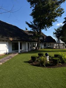 a house with a thatched roof and a yard at Thatch Haven in Mahikeng