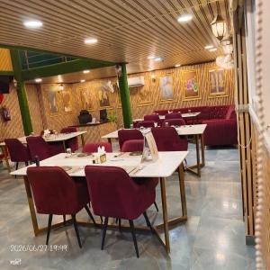 a restaurant with white tables and red chairs at AJMER TERRACES Hotel in Ajmer