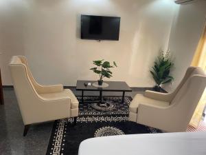 a living room with two chairs and a table and a tv at RESIDENCE Diass Immo in Diass