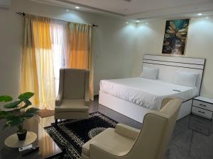 a bedroom with a white bed and a chair at RESIDENCE Diass Immo in Diass