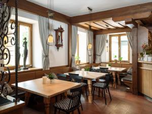 a restaurant with wooden tables and chairs and windows at Hotel Hello in Monguelfo