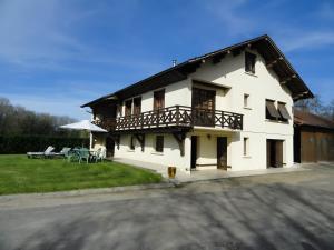 a white house with a balcony and a yard at Gite Du Moulin De Veyriat in Lescheroux
