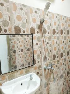 a bathroom with a shower with a sink and a mirror at Nangas Homestayy in Huu