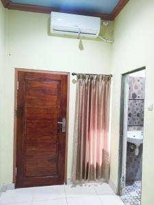 a bathroom with a wooden door and a sink at Nangas Homestayy in Huu