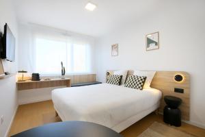 a white bedroom with a white bed and a window at Sweetly Bordeaux Mérignac Aeroparc in Mérignac