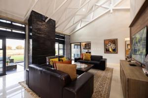 a living room with leather furniture and a fireplace at Sasavona Cottage - 349 Vaal de Grace Golf Estate in Parys