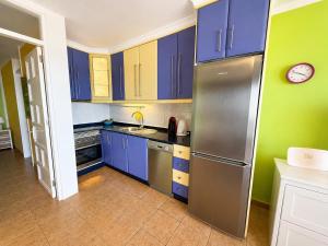 a kitchen with blue cabinets and a stainless steel refrigerator at Top augestattetes Apartment Monte Rojo in Maspalomas