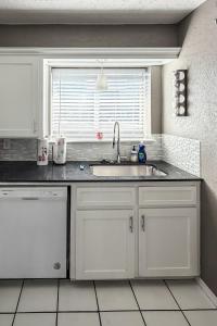 a kitchen with white cabinets and a sink and a window at Town House in Norman +29 photos