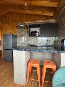 a kitchen with a counter and two orange stools at Depto huerto 23 in Puerto Natales