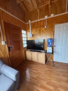 a living room with a television and a door at Depto huerto 23 in Puerto Natales