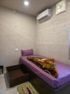 a small room with a purple bed and a heater at The Cubicle in Haldwāni