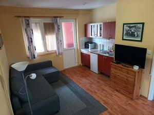 a living room with a couch and a tv and a kitchen at Basti Apartman in Gyenesdiás