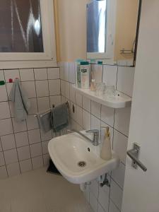 a white bathroom with a sink and a mirror at Basti Apartman in Gyenesdiás +58 photos