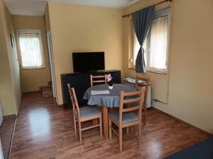 a dining room with a table and chairs and a television at Basti Apartman in Gyenesdiás