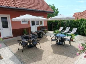 a patio with tables and chairs and umbrellas at Basti Apartman in Gyenesdiás