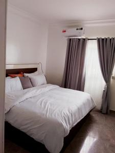 a bedroom with a bed with white sheets and a window at Modern Family Home in Ikoyi in Lagos