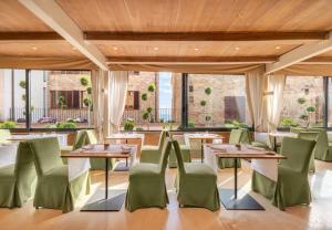 a restaurant with tables and green chairs at Borgo Tre Vaselle in Torgiano