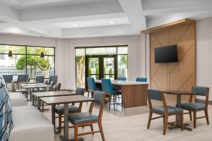 a waiting room with tables and chairs and a flat screen tv at Holiday Inn Express & Suites Memphis East by IHG in Memphis