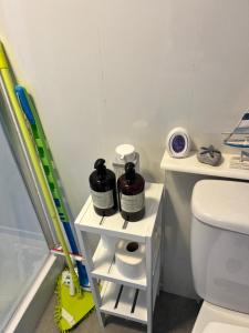 a bathroom with a toilet and a shelf with two bottles at The Lookout in Leysdown-on-Sea