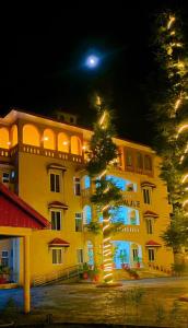 a large yellow building with a tree in front of it at Grand palace hotel kumrat in Tāl
