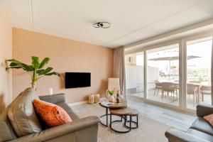 a living room with a couch and a tv and a table at Dorpsplein 42 in Callantsoog