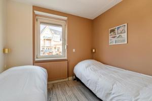 a bedroom with two beds and a window at Dorpsplein 42 in Callantsoog