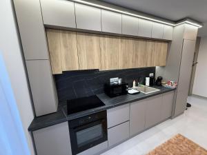 a kitchen with white cabinets and a black counter top at ViA Lux Apartman in Pécs