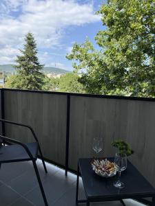 a table with a bowl of food and wine glasses on a balcony at ViA Lux Apartman in Pécs
